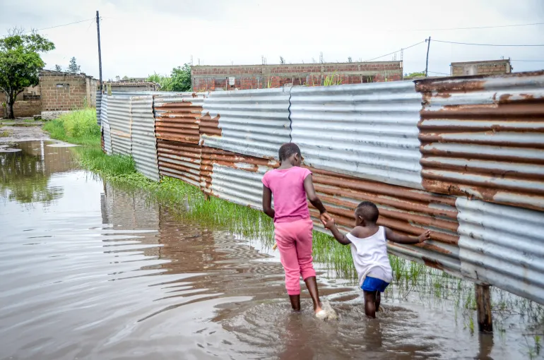 Barn vadar genom översvämningsvatten i en stadsdel i Maputo, Moçambique, fredagen den 16 januari 2026. (AP Photo/Carlos Uqueio)