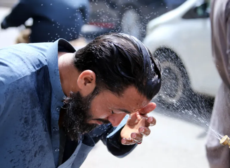 epa12934290 En volontär sprejar vatten på människor som förfriskningar under en värmebölja i Karachi, Pakistan, 5 maj 2026. Karachi förväntas förbli varmt och torrt under de kommande 24 timmarna, med temperaturer under 40 grader Celsius, sa Pakistans meteorologiska avdelning, efter en gräns på 44,1 grader Celsius och invånare rekommenderas att hålla sig till högst 44,1 grader. hydrerad. EPA/REHAN KHAN