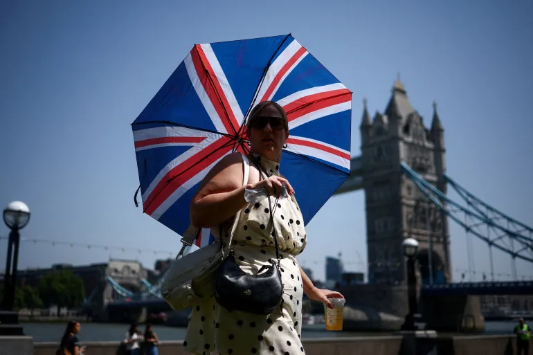 En kvinna använder ett paraply för att skydda sig från solen när hon går nära Tower Bridge, mitt i en värmebölja, när Storbritannien upplever rekordhöga temperaturer som stör skolor och transportnätverk, i London, Storbritannien, 25 juni 2026. REUTERS/Guglielmo Mangiapane TPX DAGENS BILDER