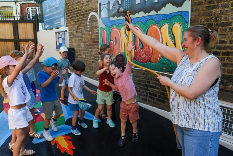 En lärare sprejar vatten på eleverna för att kyla ner dem på L'Ecole des Petits, en oberoende fransk tvåspråkig skola, när Storbritannien upplever rekordtemperaturer under en värmebölja i Fulham, London, Storbritannien, den 24 juni 2026. REUTERS/Kevin Coombs TPX DAGENS BILDER