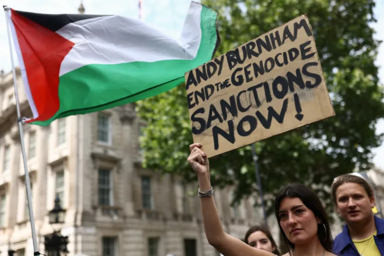 En kvinna håller ett plakat utanför Downing Street under en "Nationell mars för Palestina" uppmanar Storbritanniens nästa premiärminister, Andy Burnham, att stå upp för det palestinska folket, i London, Storbritannien, den 18 juli 2026. REUTERS/Jack Taylor