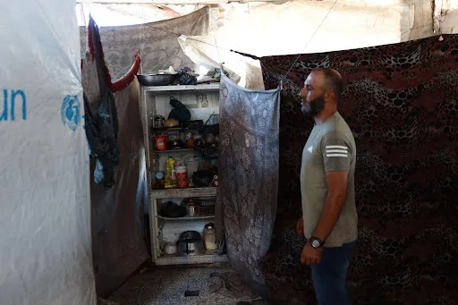 Nidal Rafeea, 40, använder sitt trasiga kylskåp som ett skåp för att förvara konserver och köksartiklar.[Abdelhakim Abu Riash/ Bladet] 