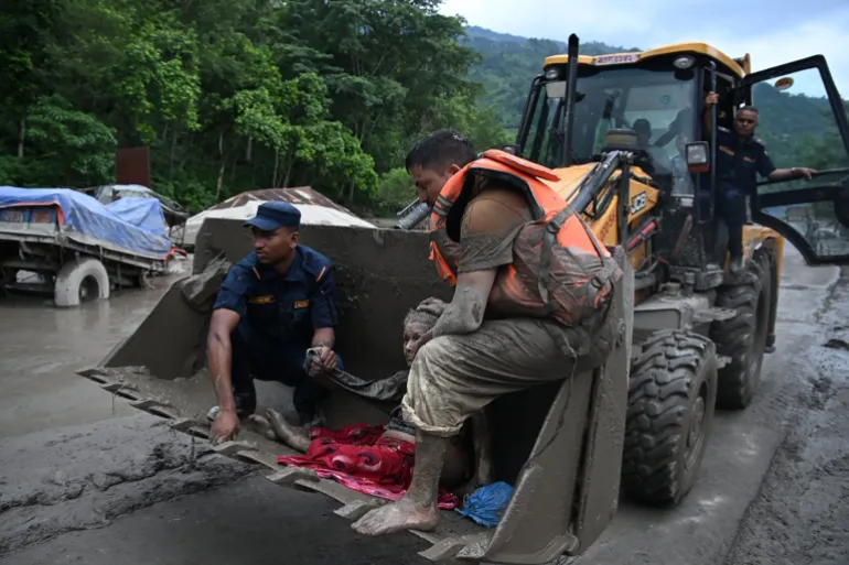 Räddningspersonal använder en grävmaskin för att bära en person som drabbats av översvämningar vid Devghat i Nepals Nuwakot-distrikt den 26 augusti 2026.