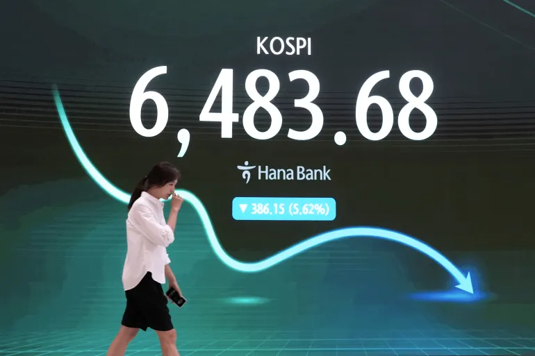 En valutahandlare går förbi en skärm som visar Korea Composite Stock Price Index (KOSPI) i valutahandelsrummet på Hana Banks huvudkontor i Seoul, Sydkorea, onsdagen den 19 augusti 2026