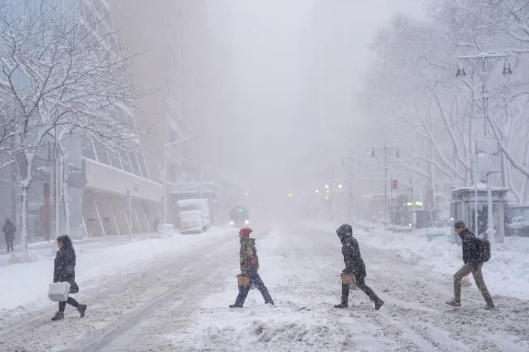 Fotgängare korsar 42nd Street under en snöstorm, den 23 februari 2026, i New York, USA