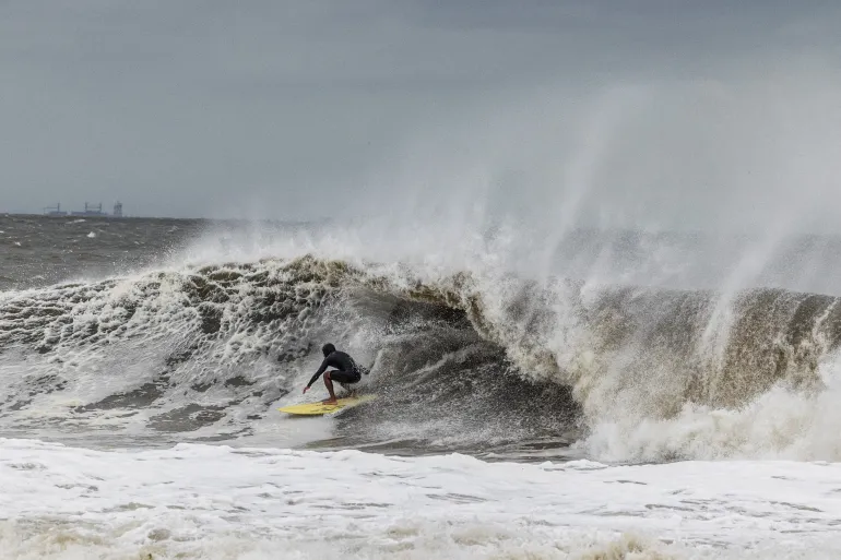 En surfare fångar en våg när en nor'easter slår mot USA:s nordöstra kust, i Rockaway, New Jersey, USA, 26 september 2026. REUTERS/Caitlin Ochs