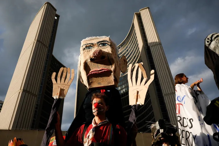 En demonstrant bär på en bild som föreställer Kanadas premiärminister Mark Carney när demonstranter samlas på Nathan Philips Square i Toronto, Kanada