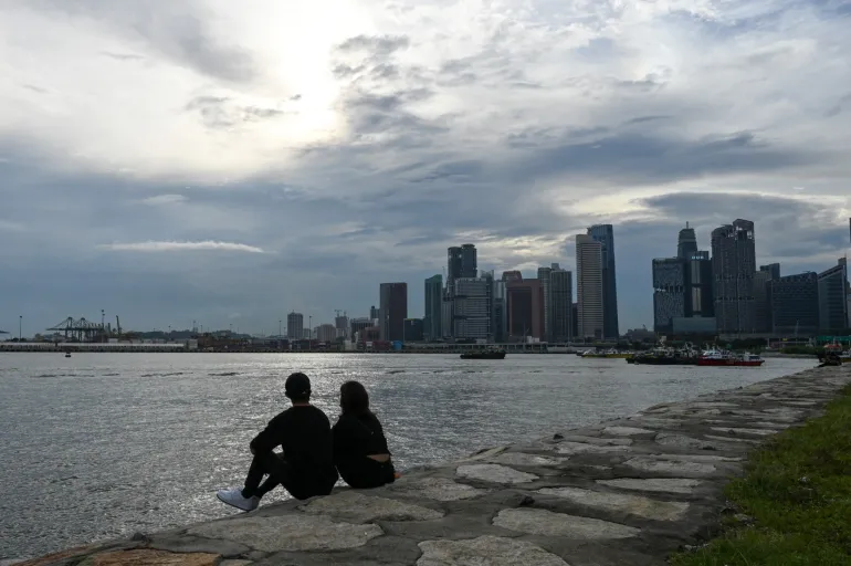 Ett par sitter längs vågbrytarklipporna i Singapore den 13 augusti 2021